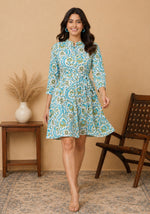Model walking toward camera in ivory A-line dress with turquoise teal botanical vine print and flowing hem movement