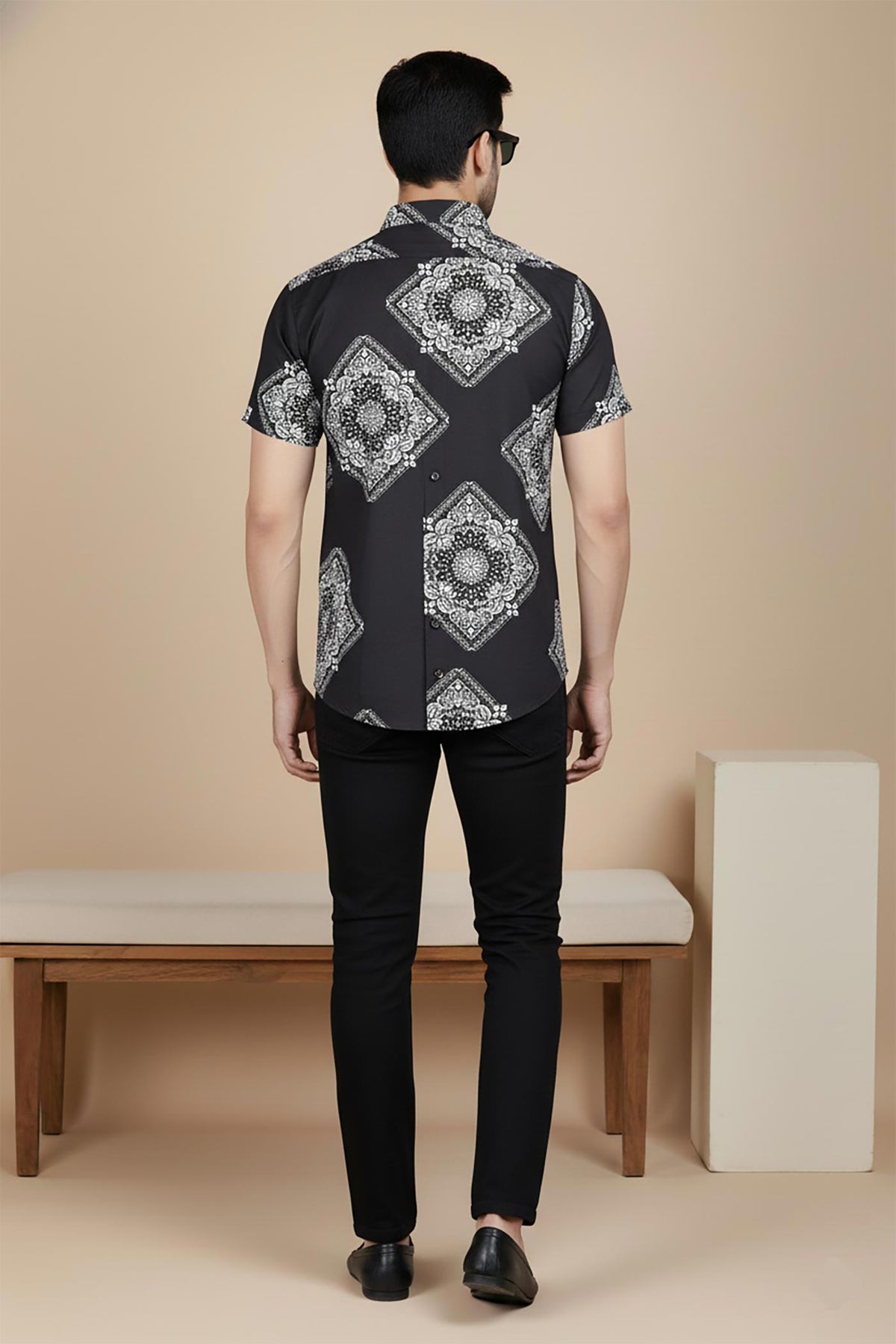 Men’s black short sleeve shirt with white bandana medallion print, back view, worn with black slim-fit trousers.