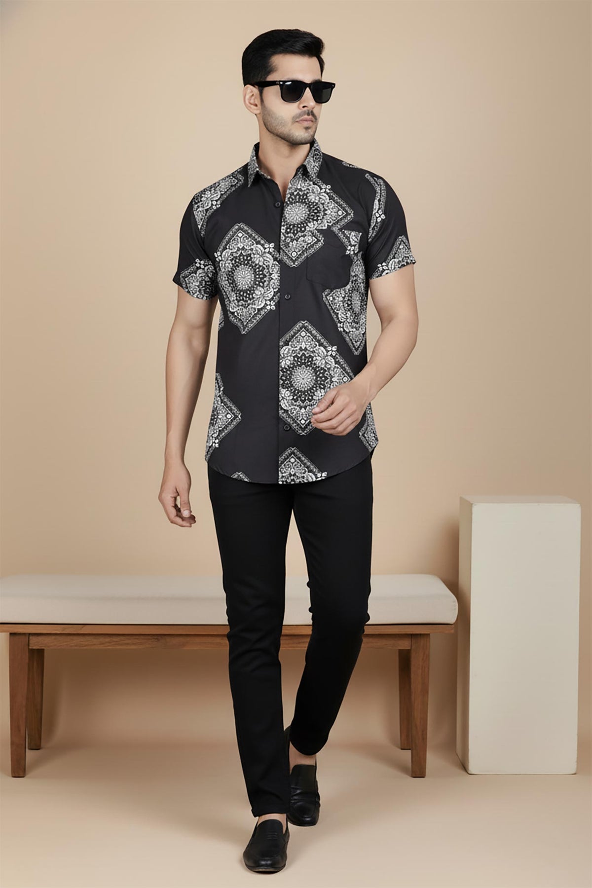 Black bandana print short sleeve shirt for men, walking pose, paired with slim black trousers and loafers.