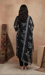 Rear view of black kurta set featuring grey floral print, sheer dupatta border, straight pants and flats.