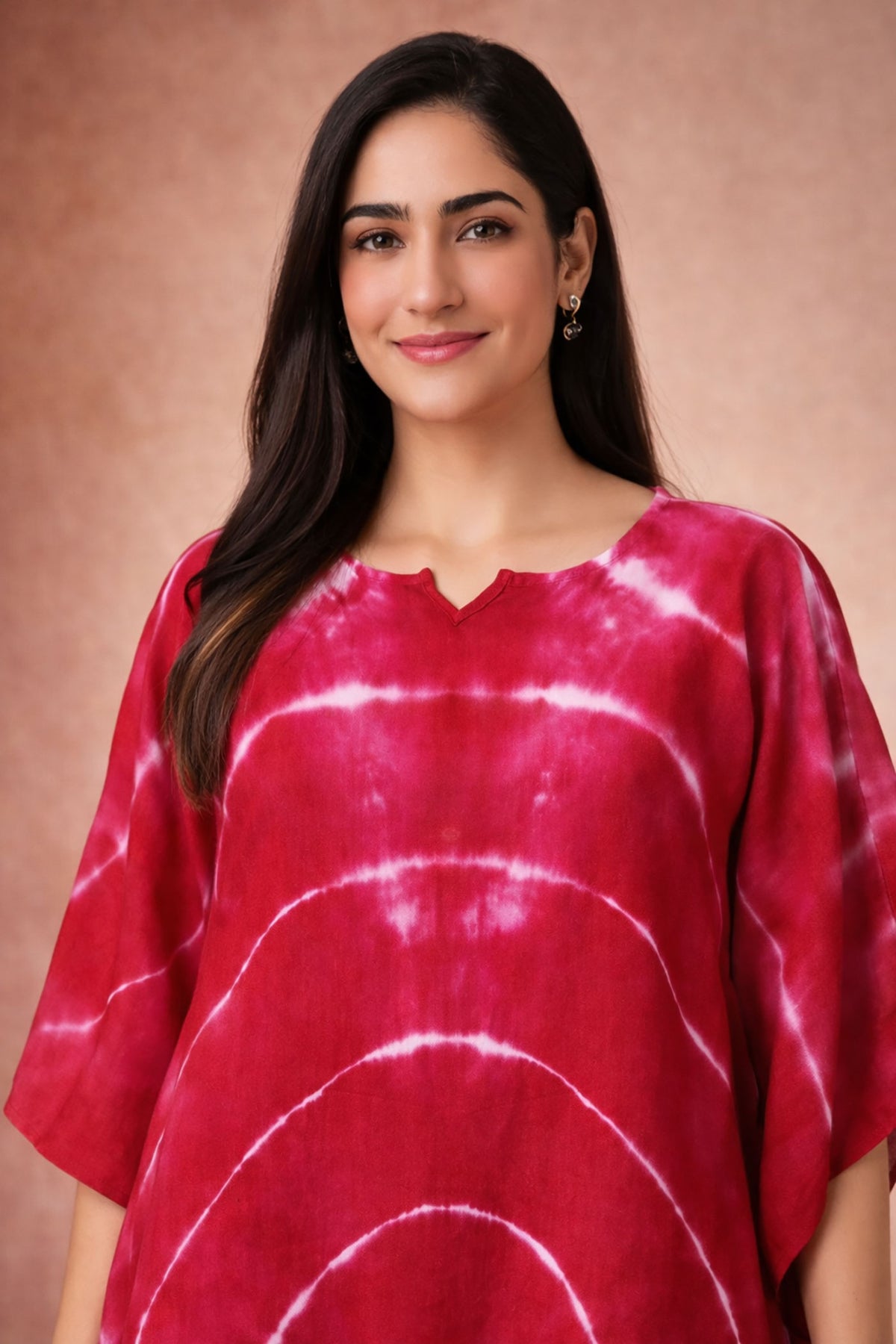 Close-up view of crimson tie-dye kaftan dress with V-notch neckline and flowy sleeves.