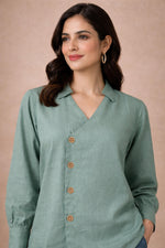 Seafoam green V-neck blouse close-up, wooden floral buttons and soft collar detail, front upper view.