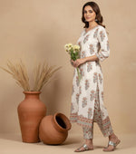 Side view of ivory floral kurta set with side slits, printed pants and peach dupatta, styled with silver flats.