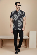 Black short sleeve men’s shirt with white bandana medallion print, front view, styled with black trousers and loafers.
