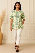 Green tie-dye oversized T-shirt with short sleeves, styled with white slim pants and black platform heels, walking front view.