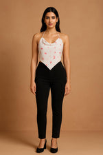 White halter handkerchief crop top with red print, front view styled with black slim-fit trousers and heels.