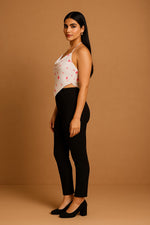White halter handkerchief crop top with red print, side view, styled with black slim pants and heels.