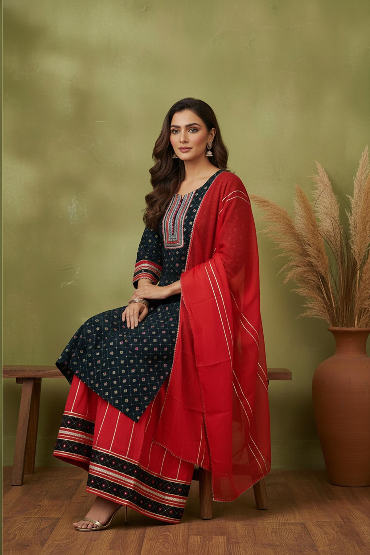 Navy cotton kurta sharara set with red dupatta, seated pose showing wide-leg sharara and sandals.
