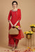 Red zari embroidered kurta palazzo set with dupatta, walking pose, styled with juttis and woven handbag