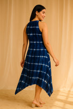 Back view of navy blue tie-dye halter neck asymmetrical midi dress with flowy hem.