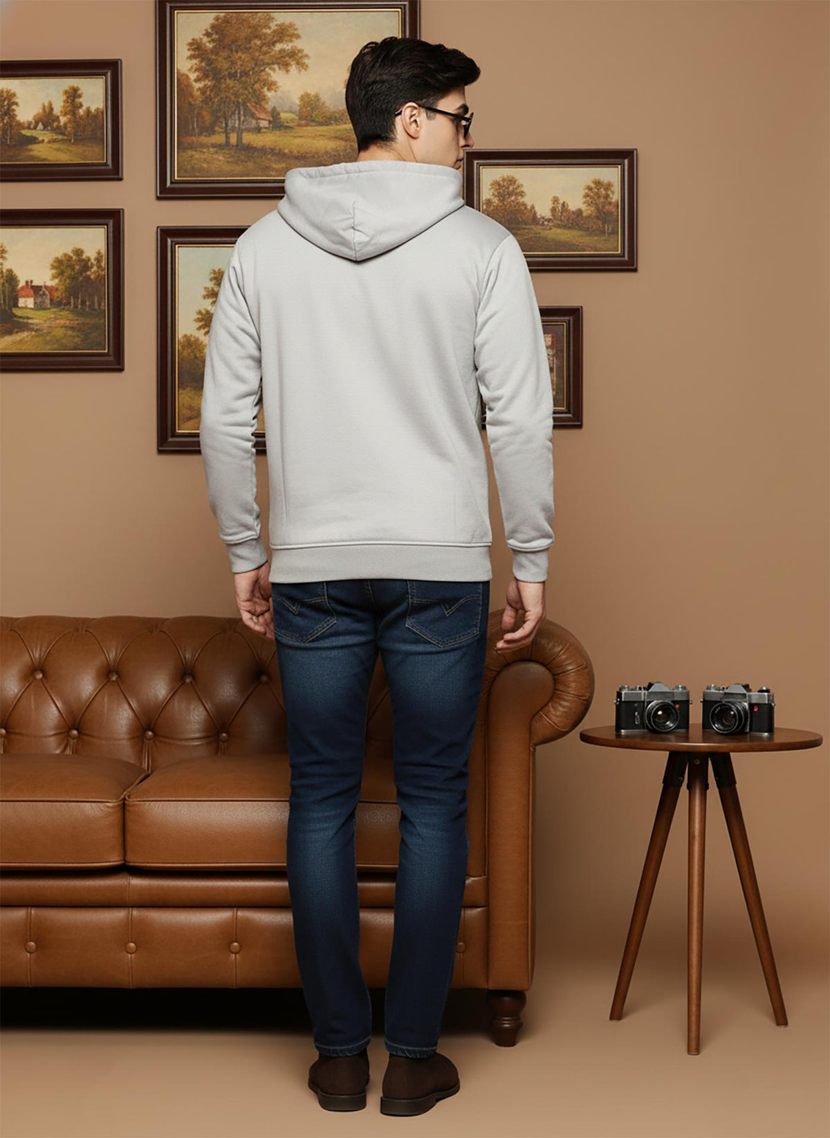 Light grey cotton zip hoodie back view featuring hood detail, ribbed hem, paired with dark denim and brown shoes.