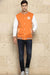 Men’s orange cotton blend varsity jacket with snap buttons and contrast sleeves, walking view styled with dark jeans and sneakers.