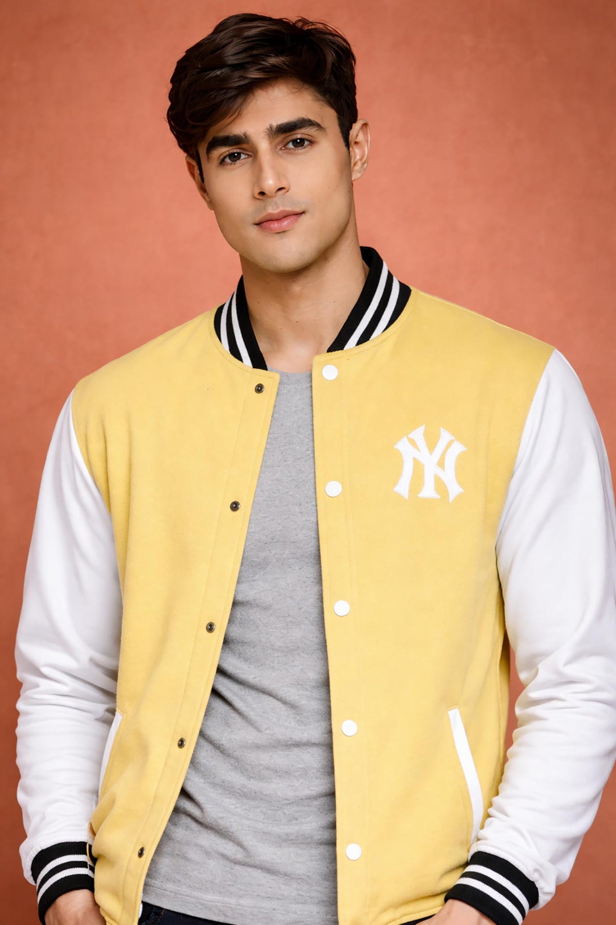 SN367 men’s pastel yellow varsity jacket closeup showing embroidered monogram and ribbed stand collar detail.
