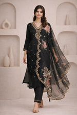 Midnight black embroidered kurta set with floral print, sheer dupatta, walking pose, beige block heels.