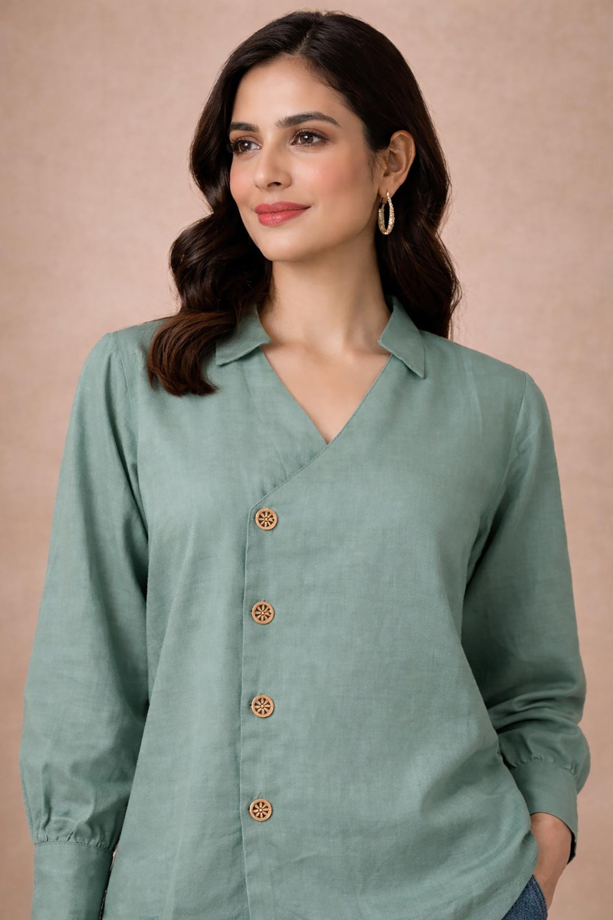 Seafoam green V-neck blouse close-up, wooden floral buttons and soft collar detail, front upper view.