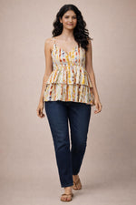 Multicolor watercolor stripe tiered camisole top with dark blue jeans, walking pose, tan sandals.