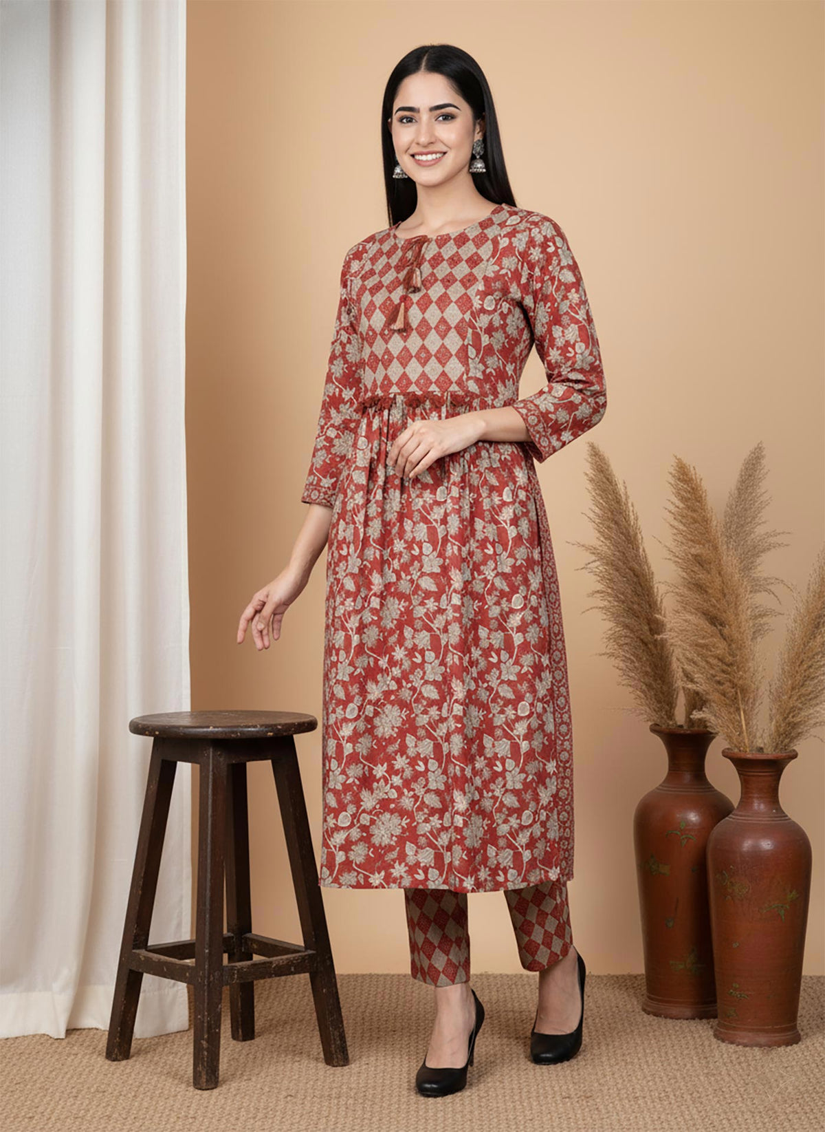 Front view terracotta floral kurta pant set with diamond yoke panel, three-quarter sleeves, styled with black heels.