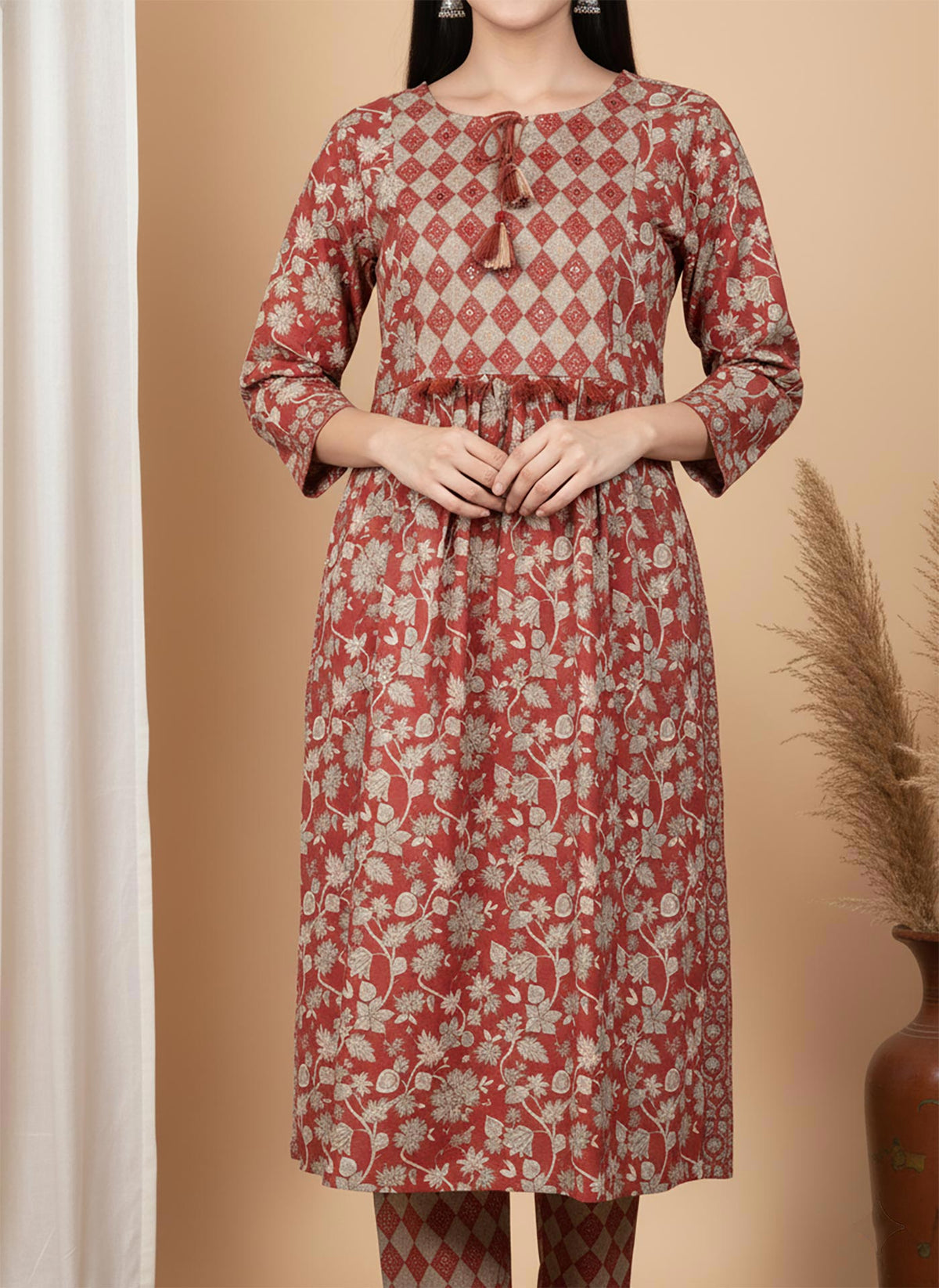 Close-up terracotta kurta diamond yoke with tassel tie-up neckline and floral print fabric.