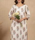 Close-up of ivory floral printed kurta with round neckline, delicate block print, three-quarter sleeves, holding white flowers.
