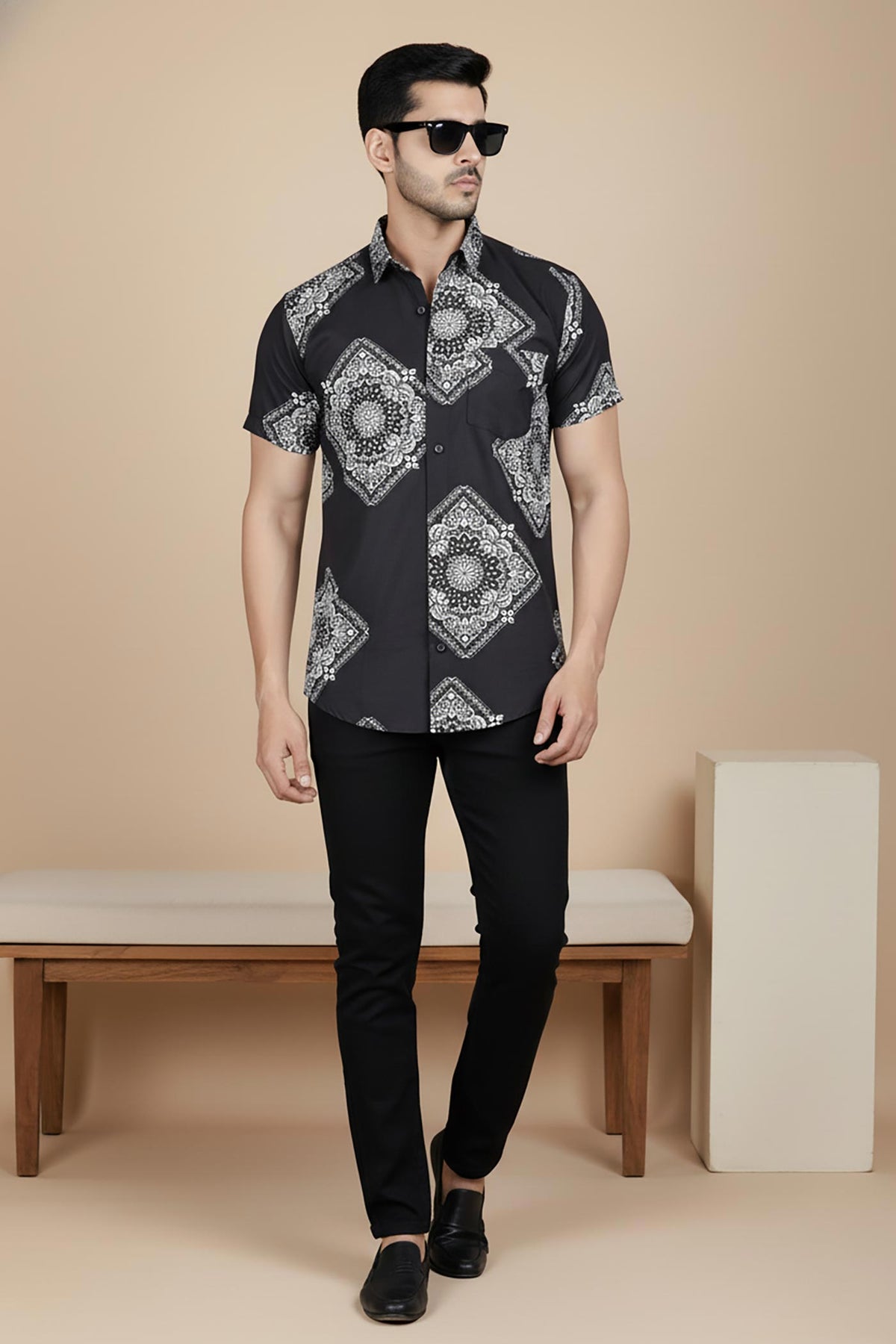 Black short sleeve men’s shirt with white bandana medallion print, front view, styled with black trousers and loafers.