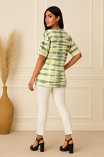 Green tie-dye oversized cotton T-shirt with short sleeves, relaxed silhouette back view styled with white fitted pants and black heels.