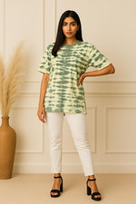 Sage green tie-dye oversized T-shirt with crew neck and short sleeves, styled with white pants and black platform sandals.