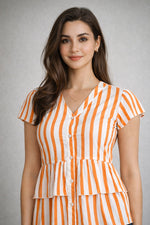Woman wearing an orange and white striped dress against a gray background