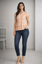 Woman wearing a striped top and blue jeans standing against a plain background