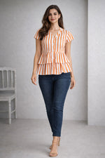 Woman wearing an orange and white striped shirt and blue jeans against a gray background