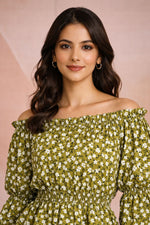 Woman wearing a green floral off-shoulder dress against a pink background